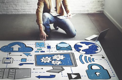 businessman kneeling next to large printout of drawings depicting the cloud
