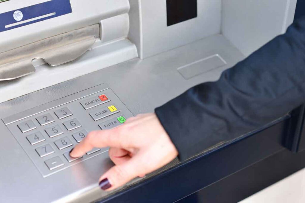 Person's hand pressing buttons on an ATM keypad