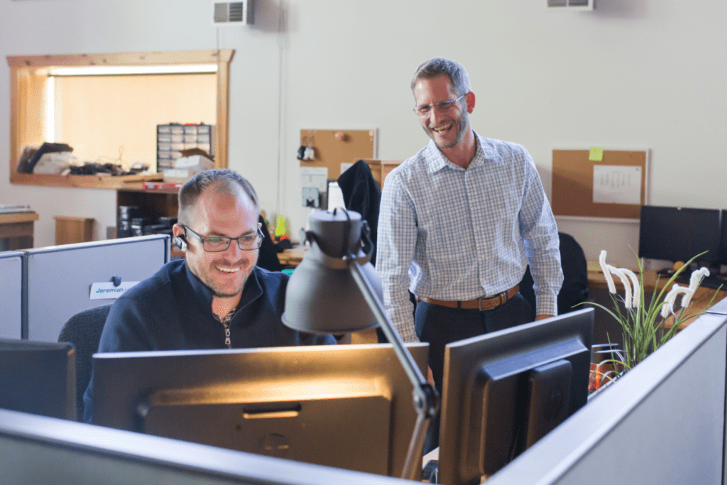 Daniel Standing behind Jeremiah Both Laughing and looking at computer screens