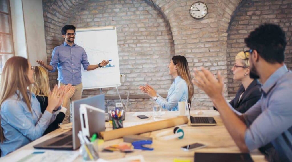 Businessman At Whiteboard Giving Presentation In Boardroom